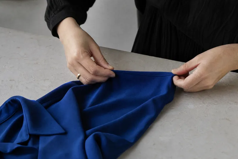 Checking the seam of a cobalt crepe shirt