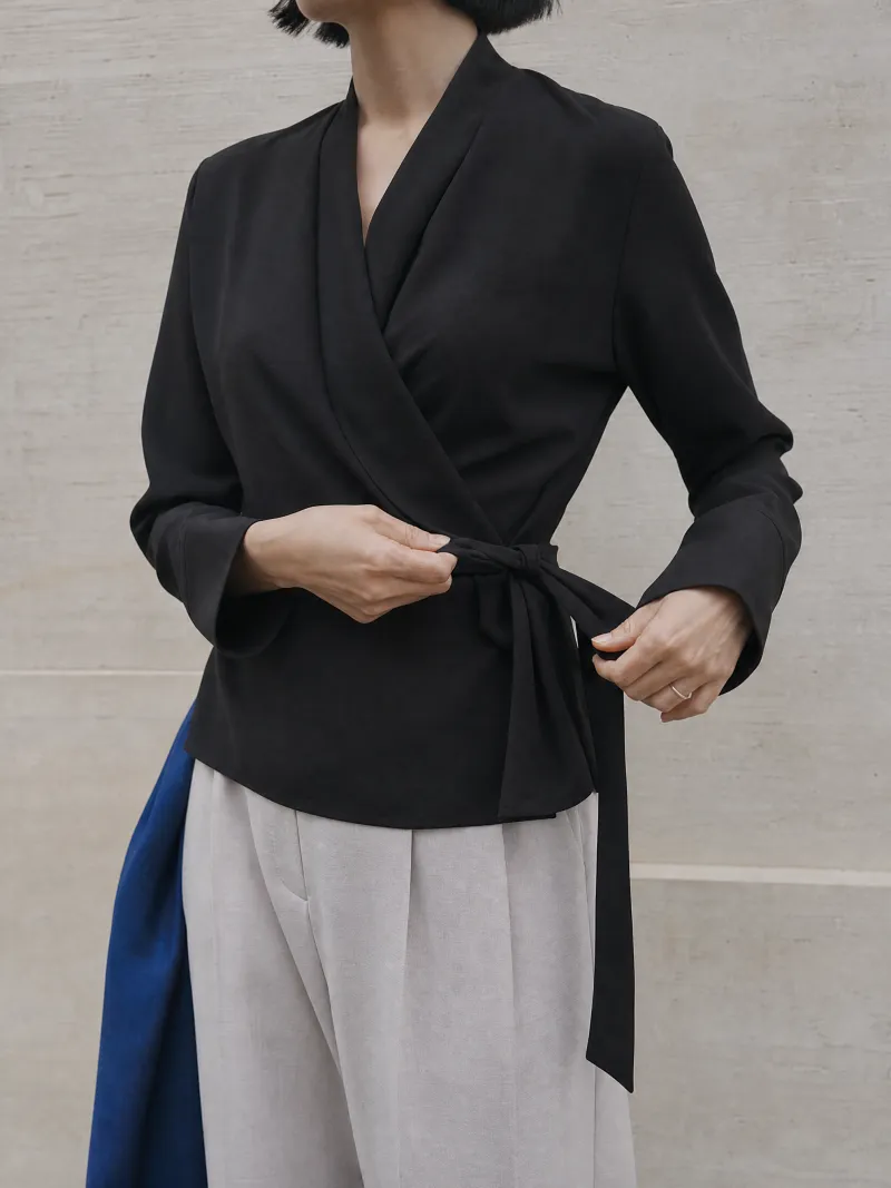 Tying the side tie of a black wrap top